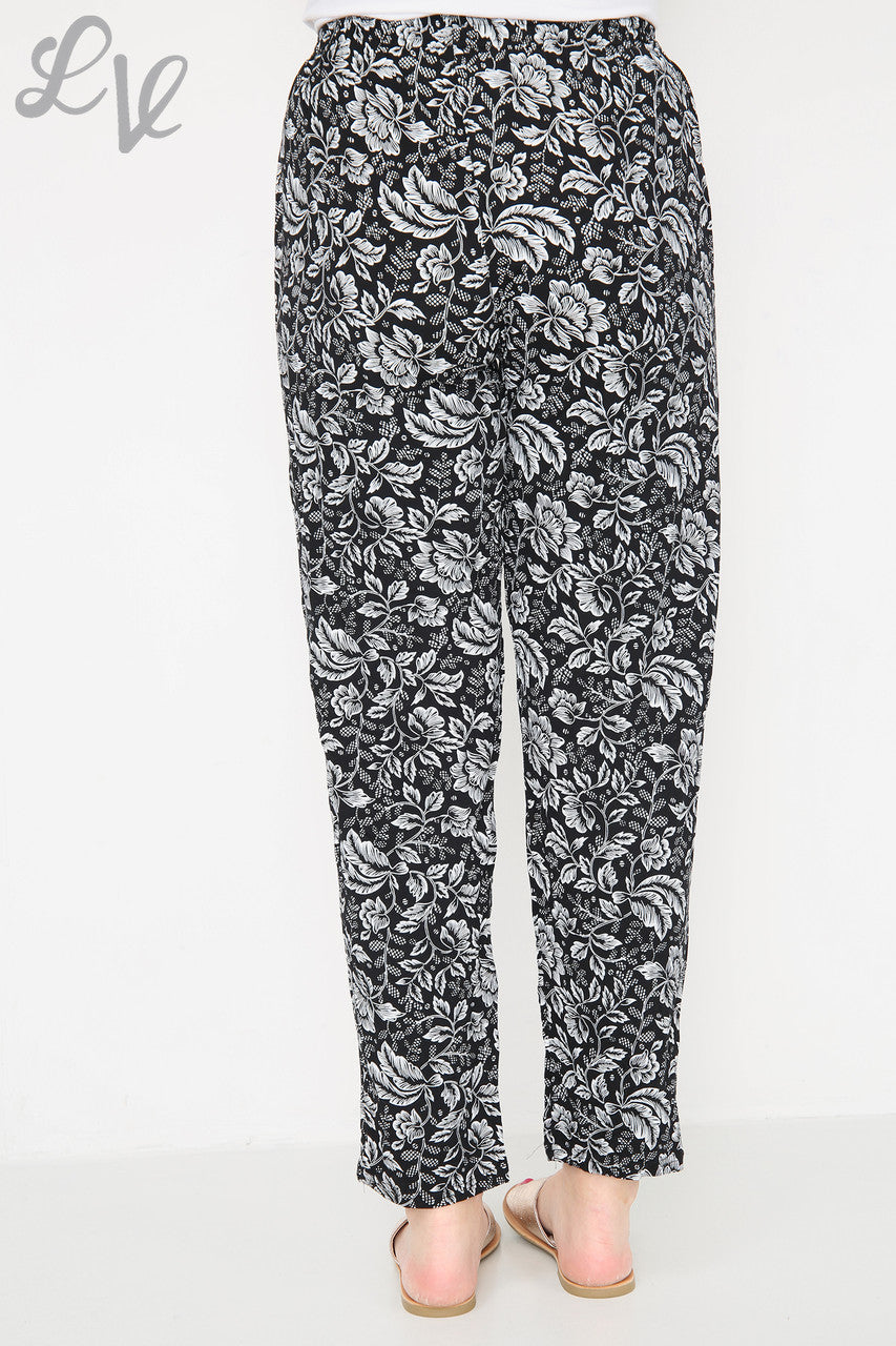 Black leaf-outline print trousers with elastic waist and ankle-length straight leg
