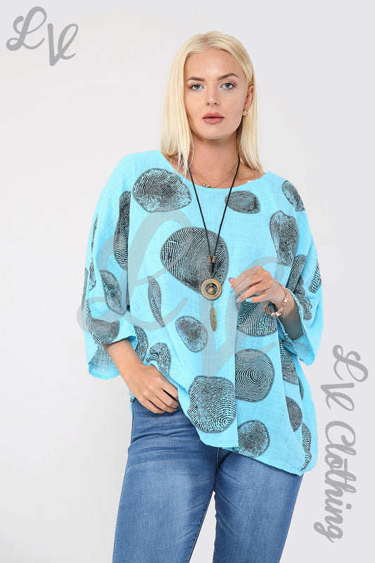 Turquoise printed top with large dark circle pattern and long black necklace