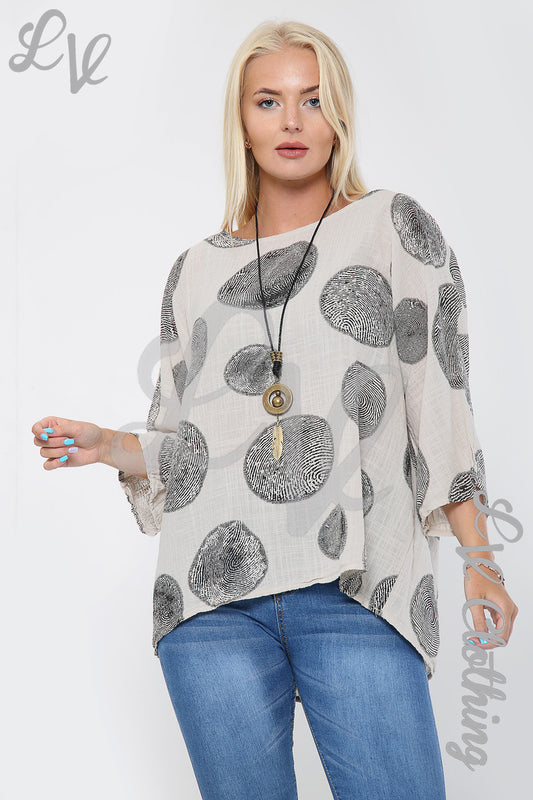Women’s printed top with gray circle pattern and long pendant necklace