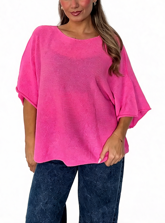 Oversized textured knit batwing top in bright pink, loose dolman sleeves, wide neckline.